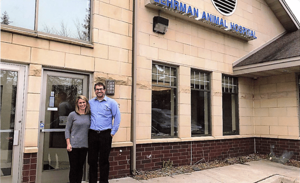Two people stand outside the entrance of a building with a sign that reads "Berman Animal Hospital.
